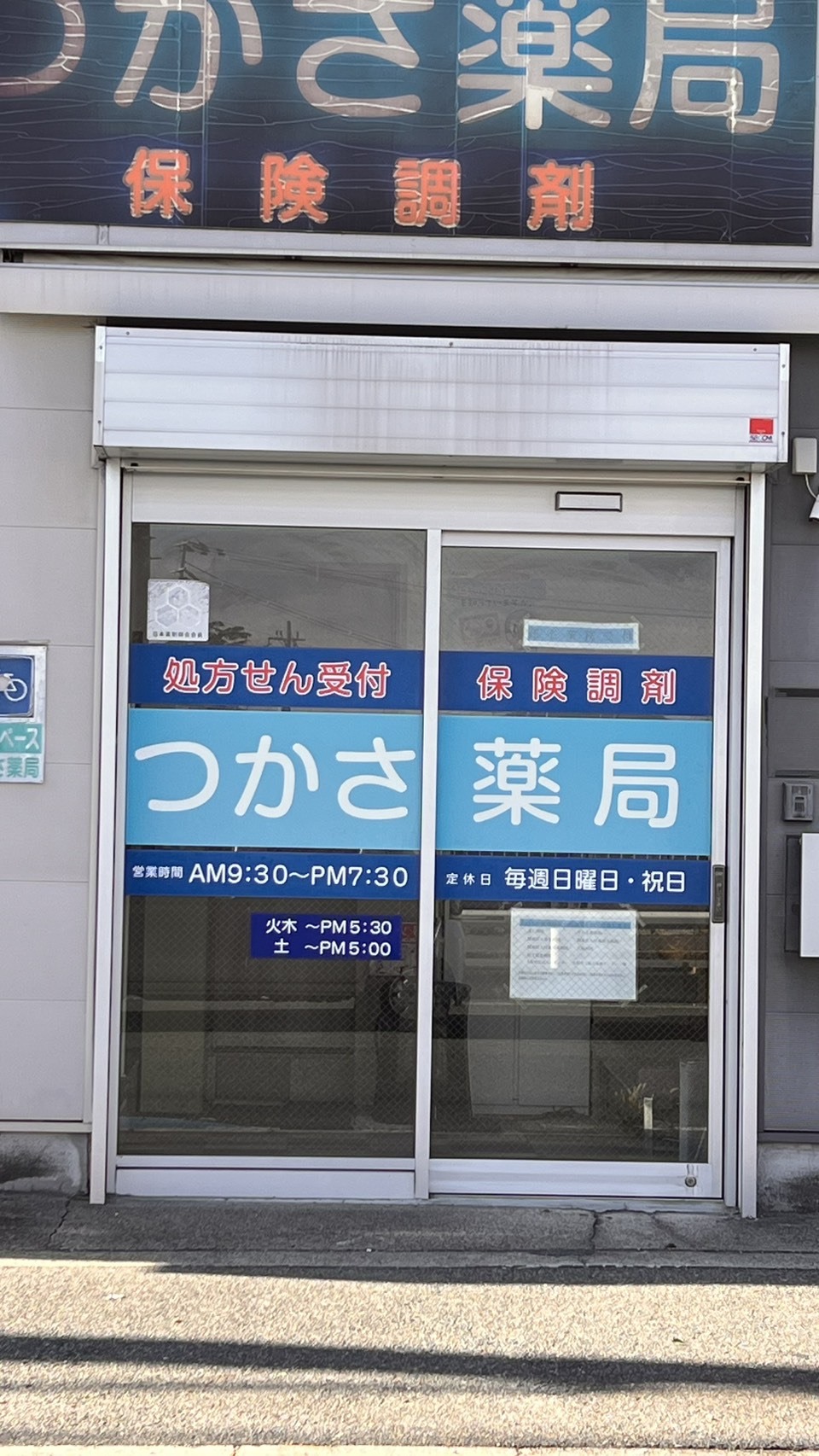つかさ薬局の入口。水色と紺のガラス面に「処方せん受付」「保険調剤」の表示
